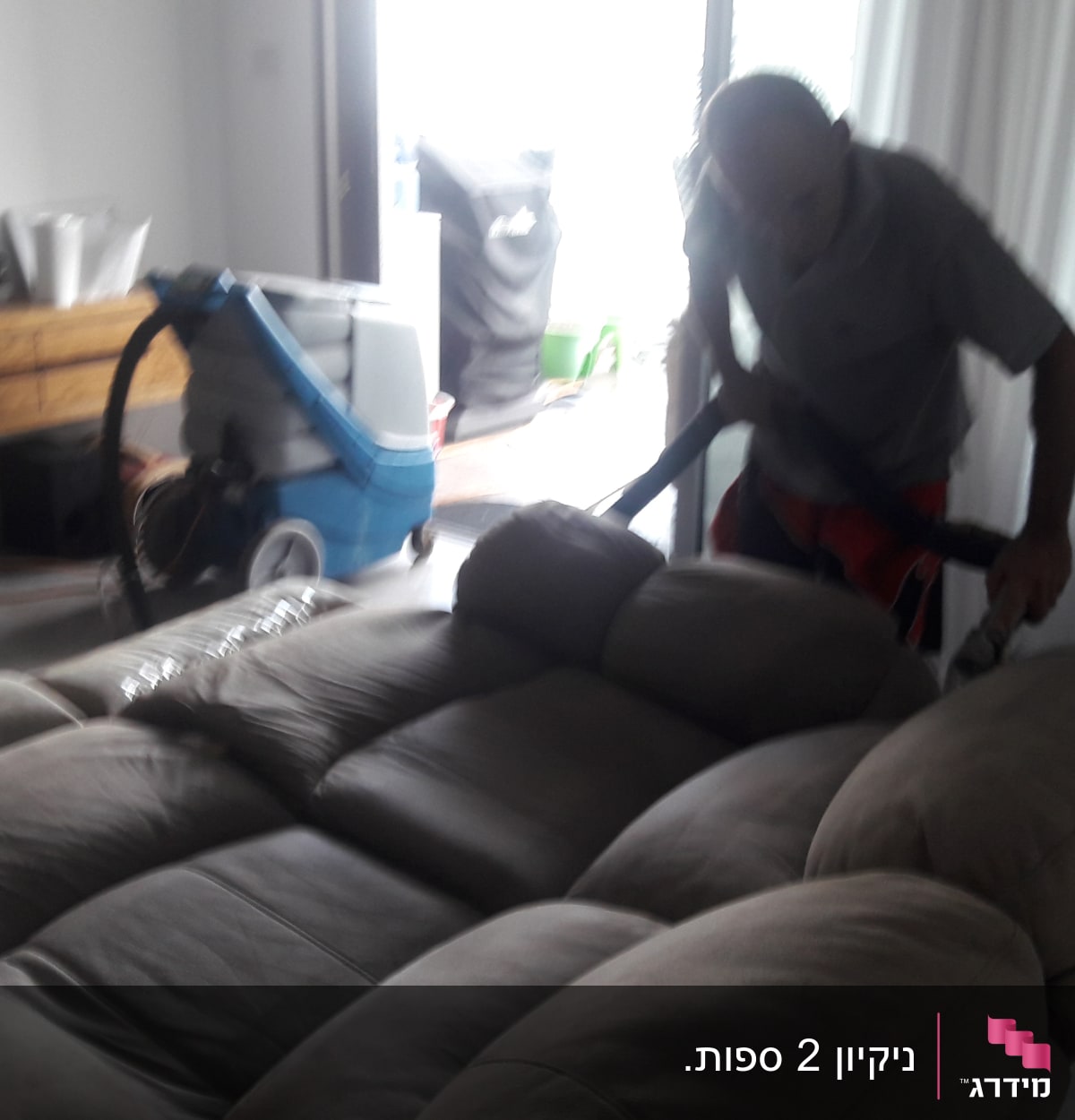 אדם מנקה ספה עם שואב אבק מקצועי